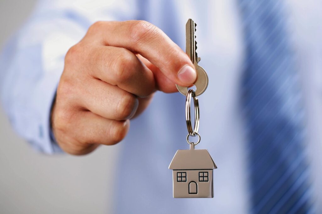 man holding a key on a house shaped keychain