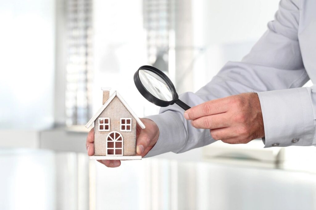 man looking at a tiny house through a magnifying glass